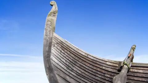 Getty Images The stern of a full-sized replica of a Viking ship, photographed against a blue sky.