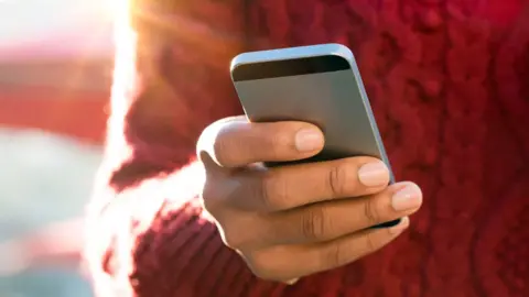 Getty Images Close up image of a young woman's hand sending a text message on a smartphone.