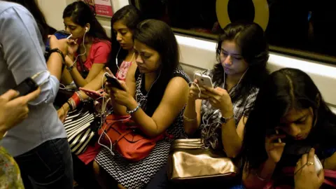 Getty Images Indian women use their smartphones as they travel in the metro carriage reserved for women in New Delhi on July 14, 2015
