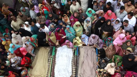 Reuters Muslim women and men gathered around three bodies in 2014