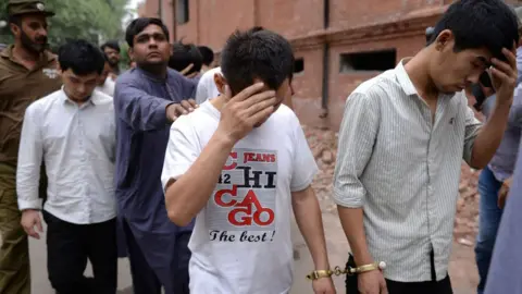AFP A Pakistani Federal Investigation Agency (FIA) official (3rd L) and a policeman escort to a court handcuffed Chinese nationals accused of allegedly luring young Pakistani girls into fake marriages then forcing them into prostitution in China, on May 11, 2019, in Lahore.