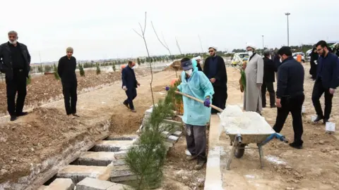Mehr news agency Worker pouring lime onto graves
