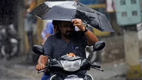 Getty Images Commuters make their way during a monsoon rainfall in Amritsar on August 1, 2022.