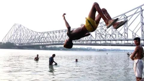Getty Images A boy jumps into the Ganges River to cool off