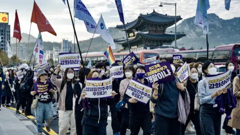 BBC Women in Seoul hold signs protesting against the government's plans to abolish the Gender Equality Ministry