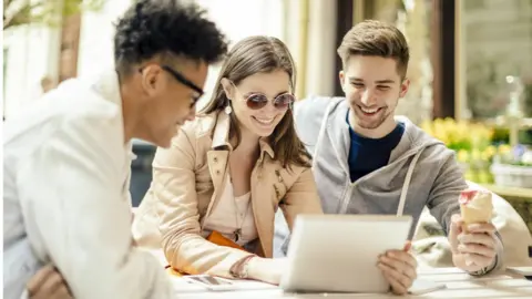Getty Images Three young people sitting around a laptop