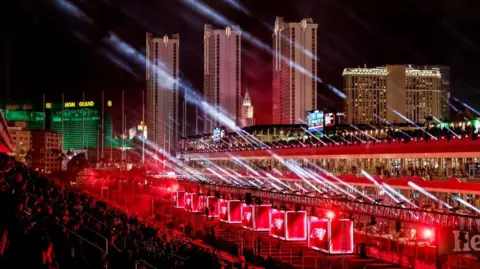  EPA-EFE/REX/Shutterstock Stands at the F1 Grand Prix in Las Vegas. Streams of light are seen coming from one storey of the stands. There are lighted boxes around a lower storey, and three towers are visible in the background.