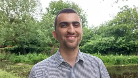 Green Party Ryan Trower wearing a striped shirt standing in a park