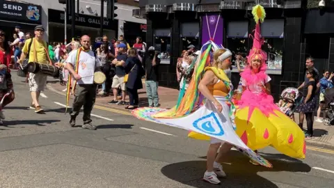 BBC/Peter Cooper Two women in a parade wearing large inflatable skirts