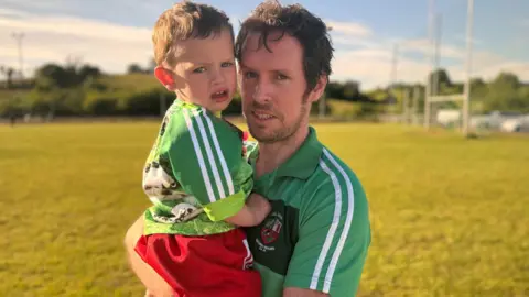 BBC Conor Holland and his son staring at the camera