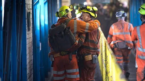 Getty Images Two men in a coal mine, one with his arm around the other (Credit: Getty Images)