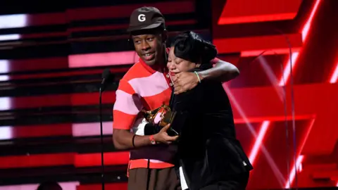 Getty Images Tyler, The Creator hugging his mum on stage, while holding the Grammy for Best Rap Album.