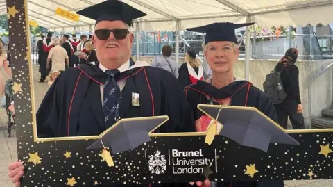 Jan Ball Ian and Jan Ball posing for a photo in a university frame