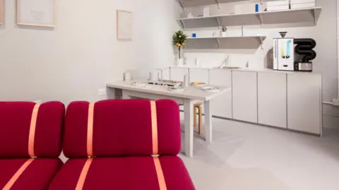 Museum of the Home  The exhibition's Innovo Room of the Future, a white room with white kitchen units, a white table and a bright red sofa