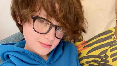 Family handout Wilf looking into the camera wearing a blue hoddie and working on his ipad