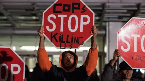 NurPhoto Protesters hold "cops stop killing us" signs