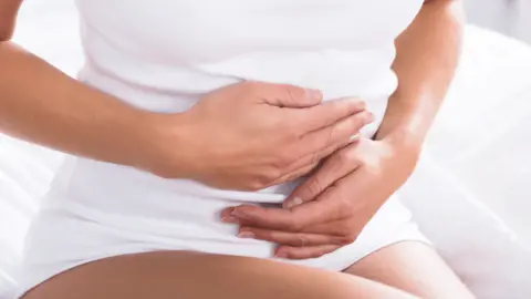 Getty Images Woman holding her stomach