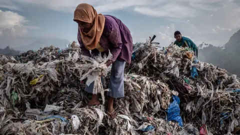 Getty Images A woman collecting plastic to recycle at a import plastic waste dump in Indonesia.