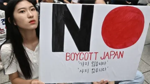AFP/Getty South Korean protesters hold a sign saying "Boycott Japan" in Seoul