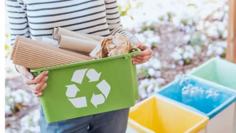 Getty Images A stock image of a young woman sorting her paper waste for recycling