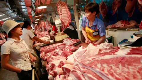 Getty Images A customer shops for pork at at butcher in China