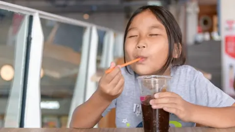 Getty Images Child with a sugary drink