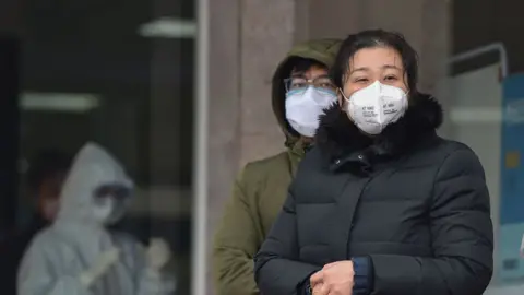 AFP/Getty People in protective masks outside Wuhan Fifth Hospital