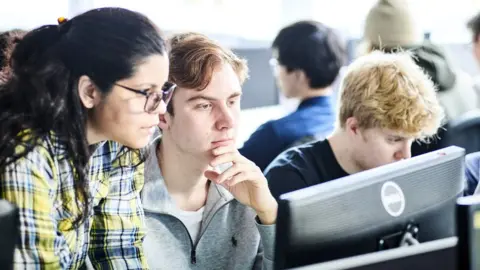 Durham University Three students - two male and one female - examine a computer screen in this photo