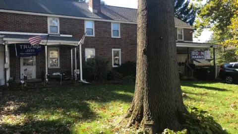 BBC A house with a Biden sign on one side, and a Trump sign on the other