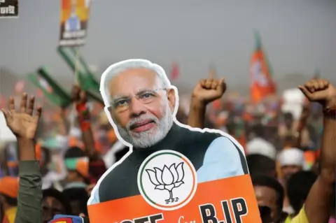 EPA Bharatiya Janata Party (BJP) supporters hold a picture poster of Prime Minister Narendra Modi during a rally by the Indian prime minister Narendra Modi at Brigade Parade Ground in Kolkata, India, 07 March 2021.