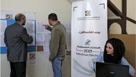 AFP Palestinian officials look at electoral lists in Hebron (06/04/21)