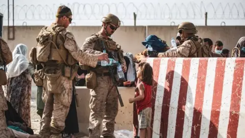Reuters U.S. Marine hand out water during an evacuation at Hamid Karzai International Airport