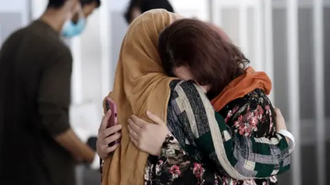 AFP A woman embraces her sister-in-law as she arrives with other Afghan refugees