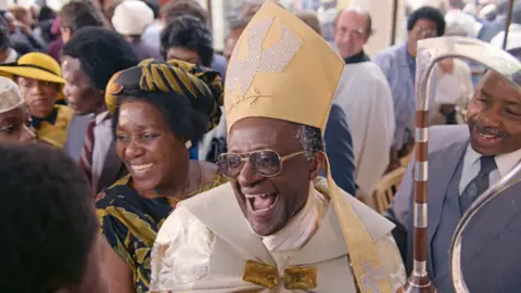Getty Images Desmond Tutu smiles after being appointed Anglican Archbishop of Cape Town in 1986, with his wife, Leah, is at his side