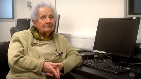Rhondda Cynon Taf CBC Margaret sitting in beside a computer