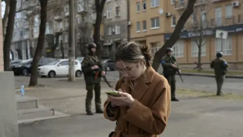 BULENT KILIC Woman on a mobile phone standing in front of Ukrainian soldiers