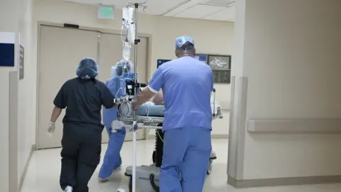 Getty Images Hospital staff push a patient on a gurney