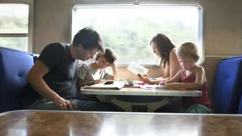 Getty Images Family sat at a train table