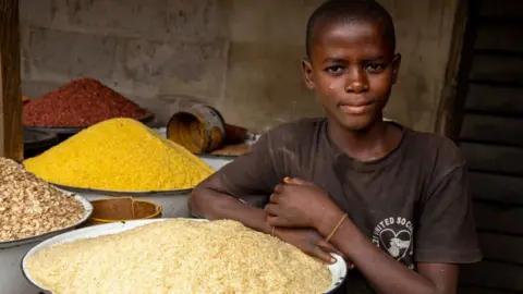 Getty Images A young boy poses next to some rice in his shop at Ajara Market in Badagry, near Lagos, on September 6, 2019