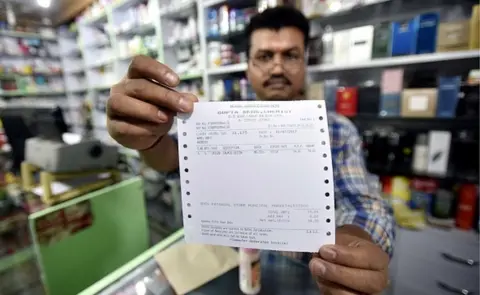 Getty Images A shopkeeper showing new updated GST bill outside the store at Connaught place on July 1, 2017 in New Delhi, Indi