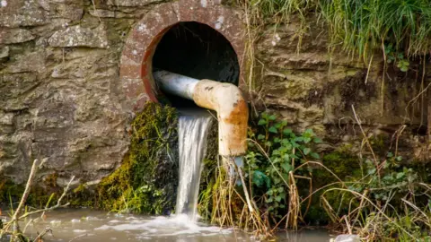Getty Images Water flows from a drain into a river in the UK