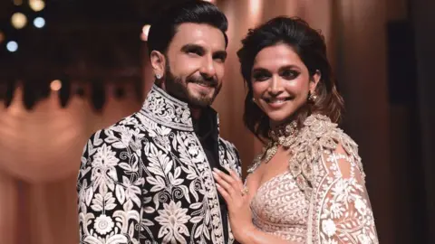 Getty Images In this picture taken on July 29, 2022, Bollywood actors Ranveer Singh and Deepika Padukone walk the ramp for Mijwan Welfare Society and fashion show by designer Manish Malhotra in Mumbai.