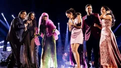 Reuters Mukesh Ambani, the Chairman of Reliance Industries, Isha Piramal, Rihanna, Shloka Mehta Ambani, Akash Ambani and Radhika Merchant react on the stage during pre-wedding celebrations of Anant and Radhika in Jamnagar, Gujarat, India, March 1, 2024.