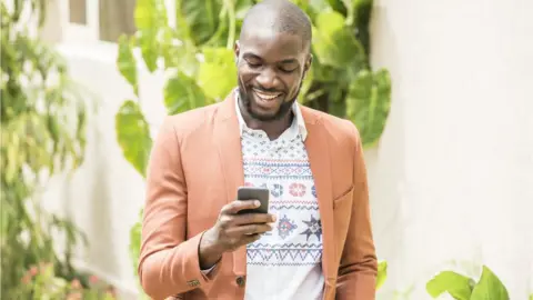 Getty Images Smiling man checking his phone