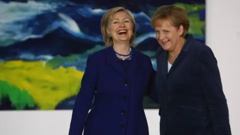 Sean Gallup Hillary Clinton and Angela Merkel laughing together