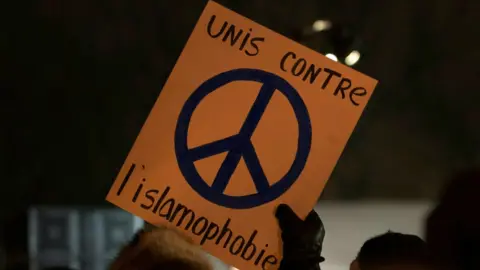 AFP A person holds a sign 'United against Islamophobia'