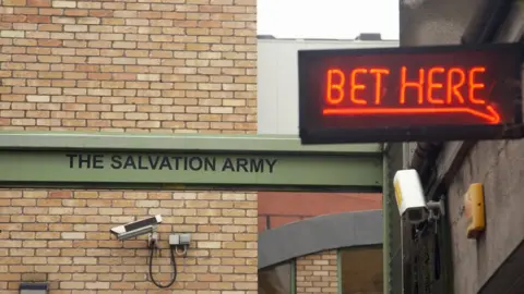 Getty Images An alley with a neon sign saying 'Bet Here' next to a Salvation Army sign
