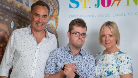 Bernadette John A son with his parents look into the camera. 