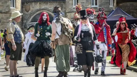 Danny Lawson/PA  Steampunks walking through Lincoln's historic quarter. Outfits range from black to red, with some wearing brightly-coloured wigs, or top hats and goggles