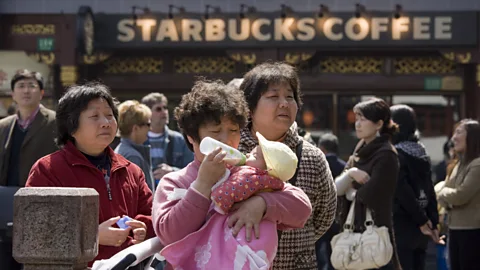 Tim Graham/Getty Images Woman feeds baby outside Starbucks in the Yu Garden Bazaar, China (Credit: Tim Graham/Getty Images)